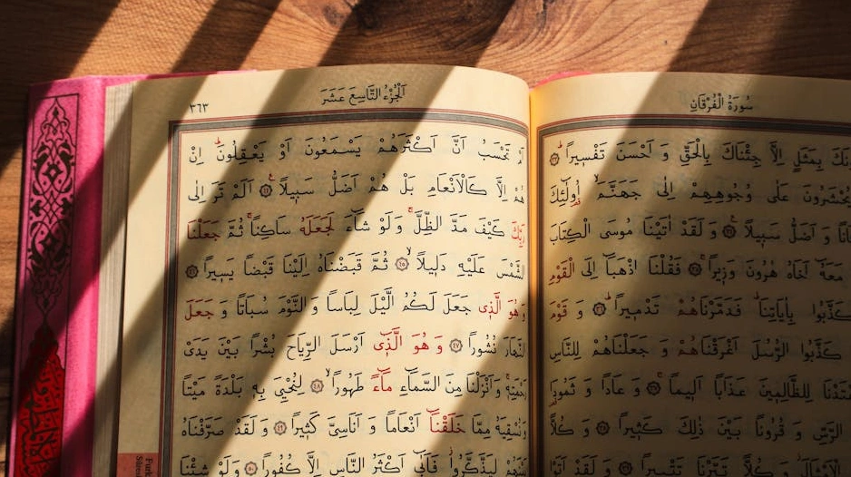 Otevřená kniha s historickými dokumenty a zlatou mincí na stole.